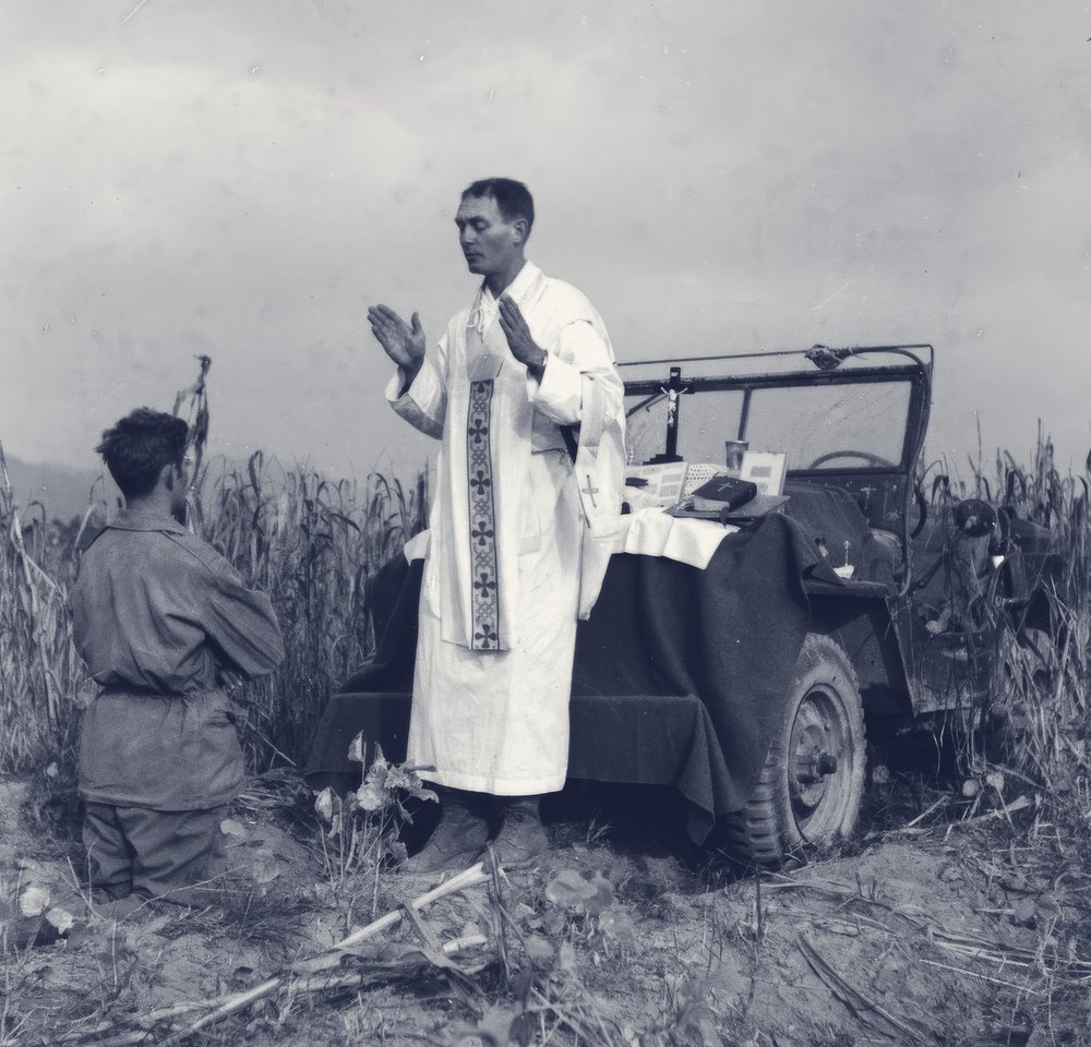 Father Emil Kapaun celebrating a battlefield Mass on the hood of a jeep in Korea, 1951