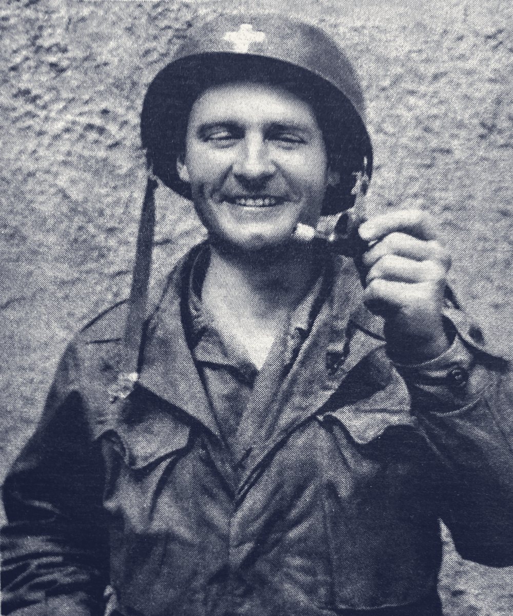 Father Emil Kapaun in helmet and field jacket holding his pipe, broken during a raid in the Korean War